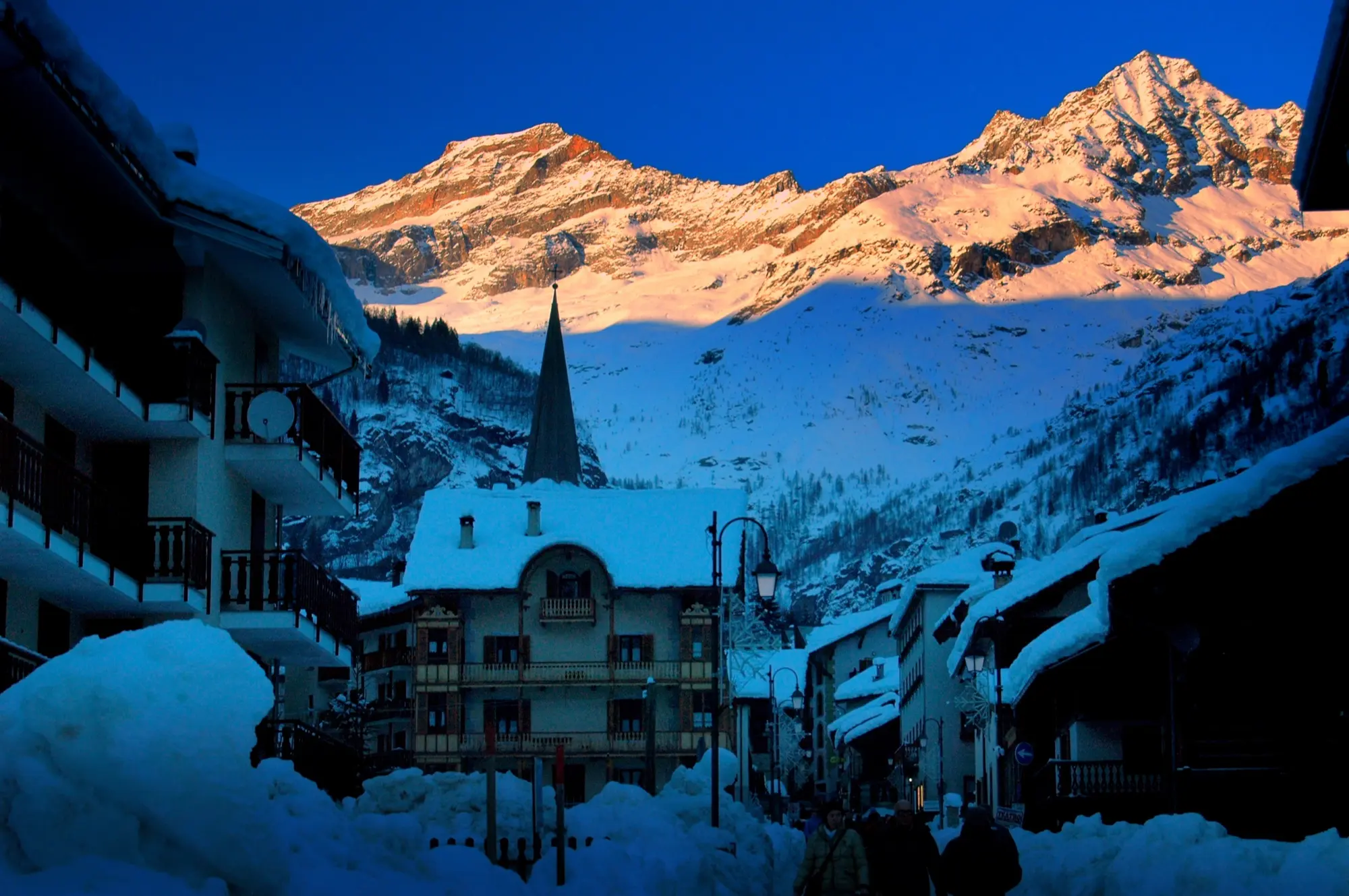 Alagna Valsesia in winter at dusk, with the Monte Rosa massif lit pink above the village