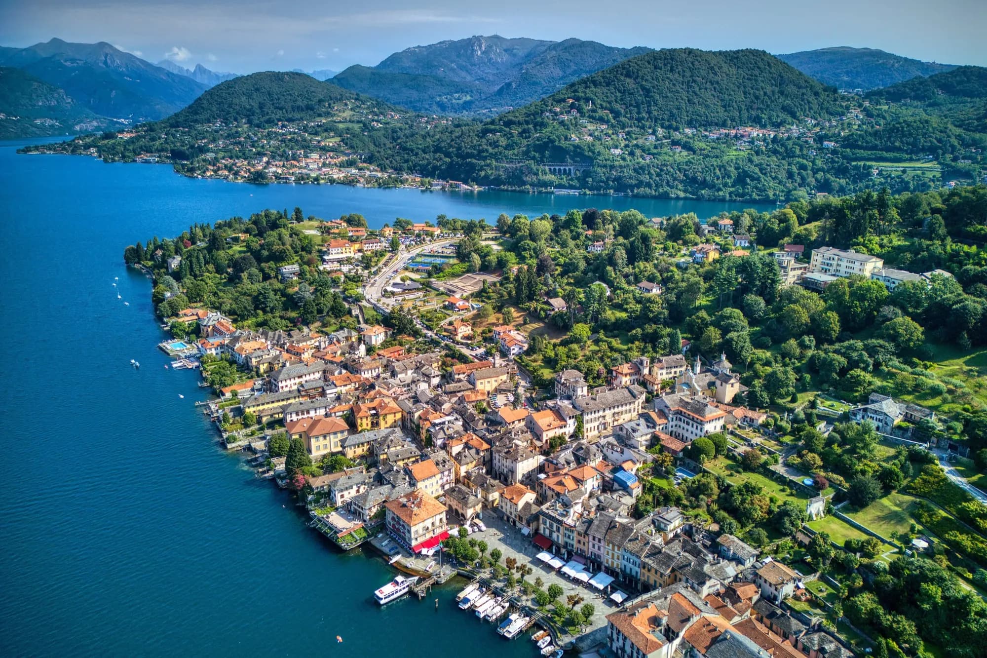 Aerial view of Orta San Giulio on its peninsula, with Lake Orta and wooded hills behind