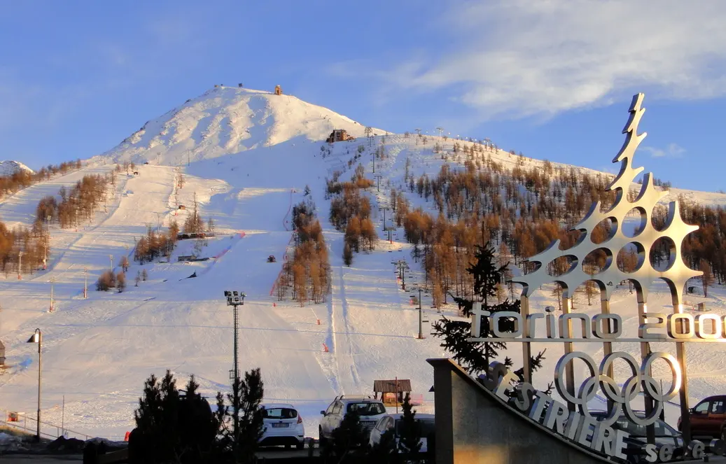 Snowy ski slopes at Sestriere with the Torino 2006 Olympic monument in the foreground