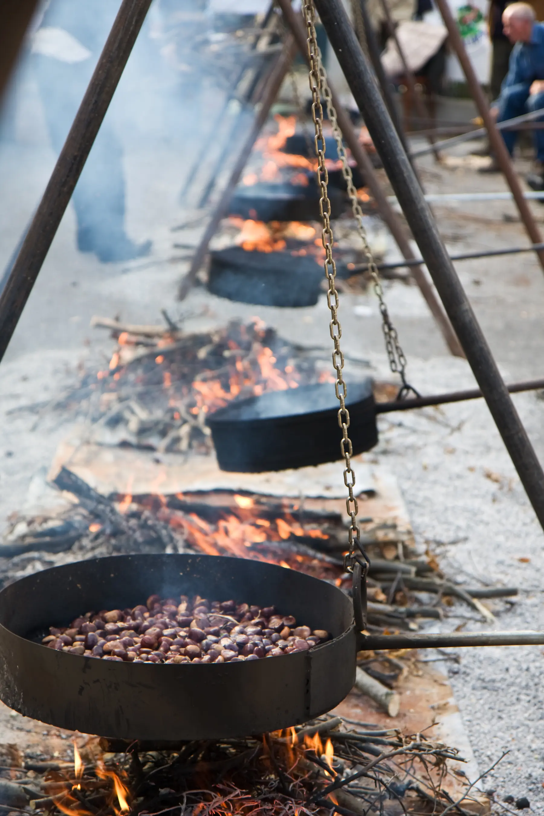 Roasted chestnuts (caldarroste) cooking in pans at a street stall in Italy